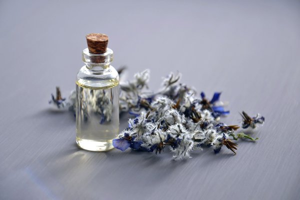 Essential oil vial surrounded by white and purple flowers